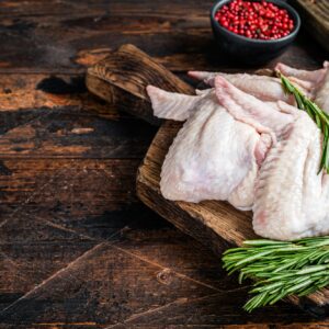 Uncooked Raw chicken wings Poultry meat on a butchery board with meat cleaver.