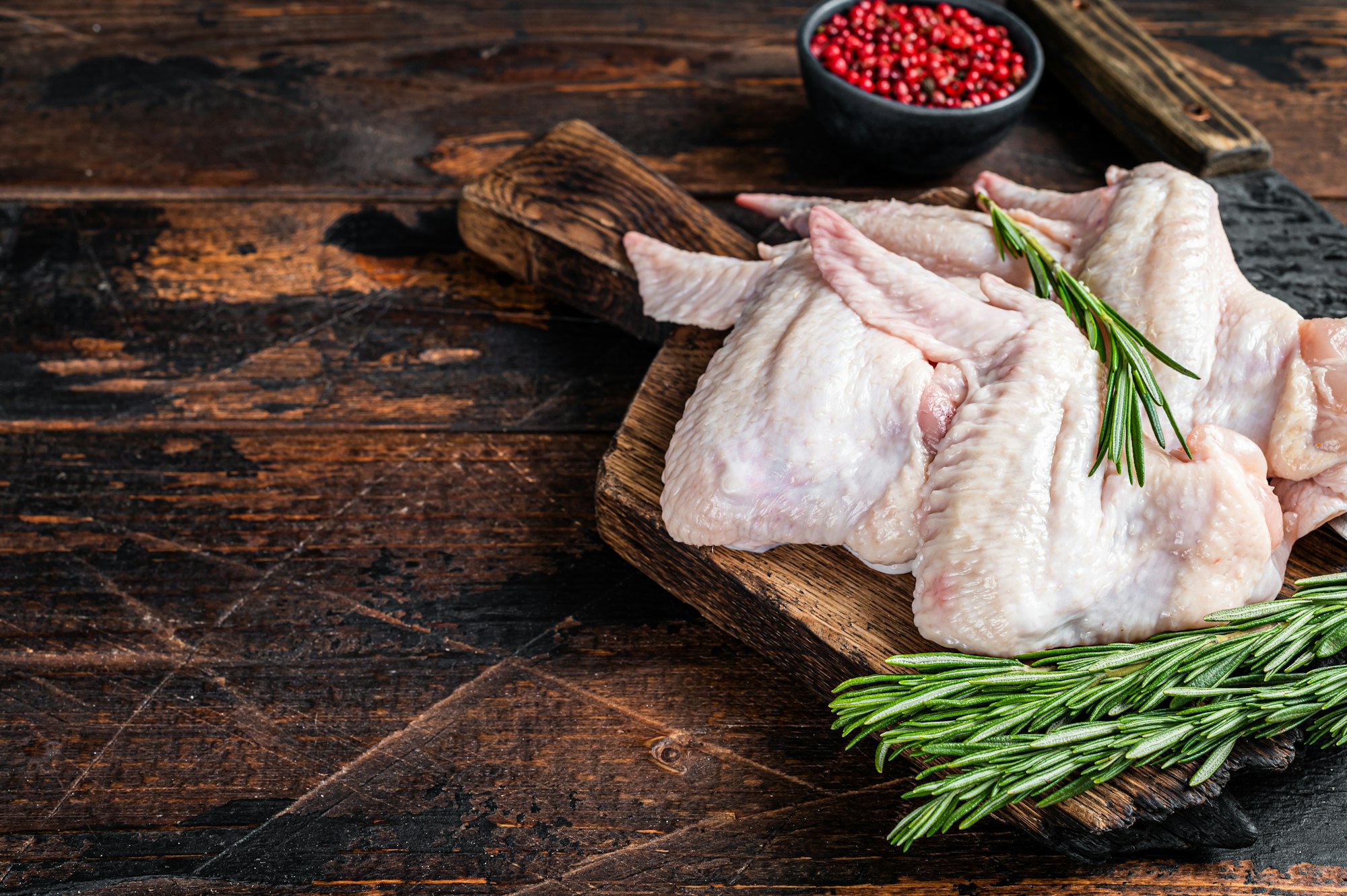 Uncooked Raw chicken wings Poultry meat on a butchery board with meat cleaver.
